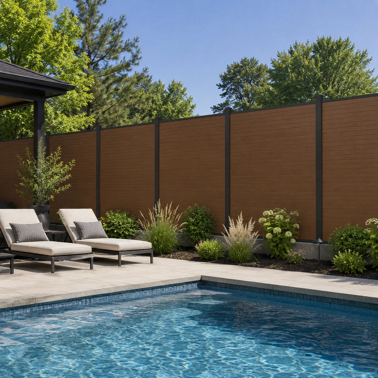 Premium composite privacy fence in wood finish installed alongside a modern backyard swimming pool with lounge chairs.