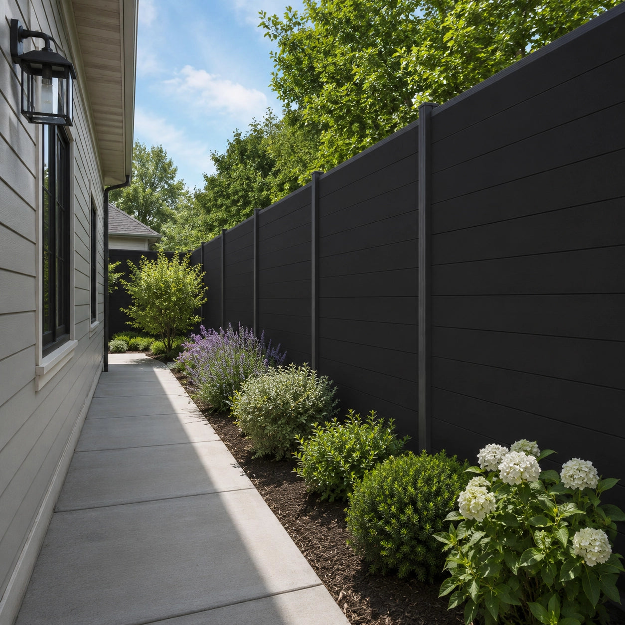 Corner installation of 6ft wide black aluminum full privacy fence panel in a residential yard.