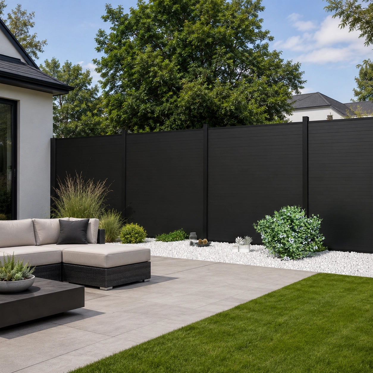 Sleek black composite privacy fence panels providing a modern backdrop for a backyard lawn and patio sectional sofa.